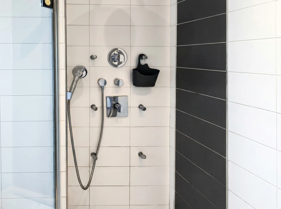 Cabine de douche moderne avec paroi en verre, carrelage blanc rectangulaire et frise verticale en grès cérame anthracite