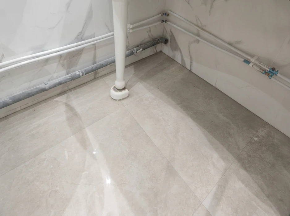 Salle de bains en cours d'installation, sol en carrelage marbre beige poli, murs habillés de marbre blanc veiné