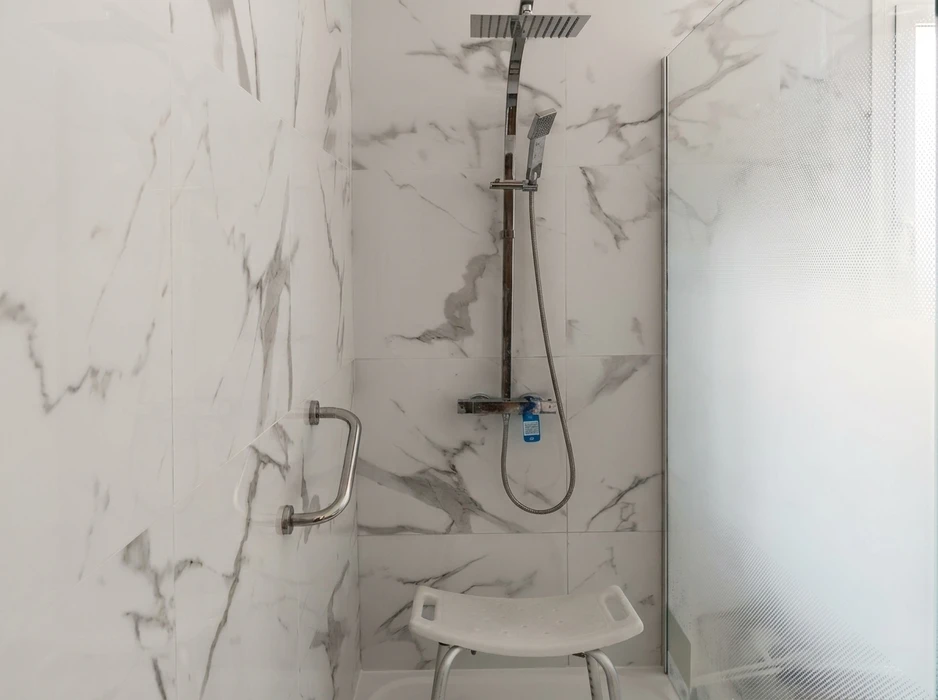 Salle de bain moderne avec douche à l'italienne, vasque ronde blanche sur plan de travail en bois, robinetterie noire mate