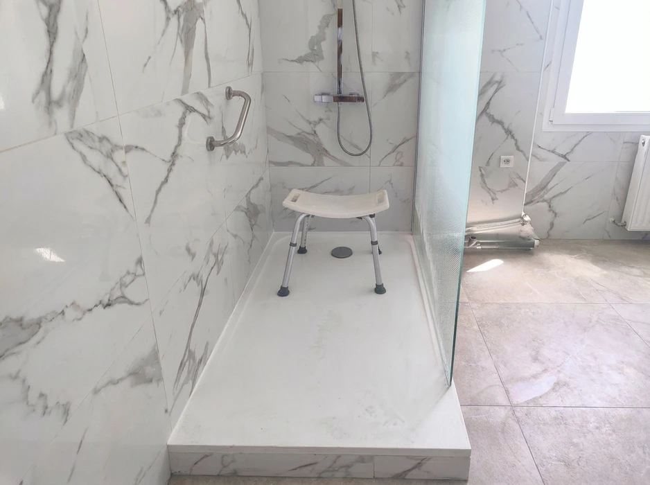 Salle de bain moderne avec douche à l'italienne, carrelage blanc et gris, receveur de douche carrelé, paroi de douche en verre, colonne de douche thermostatique