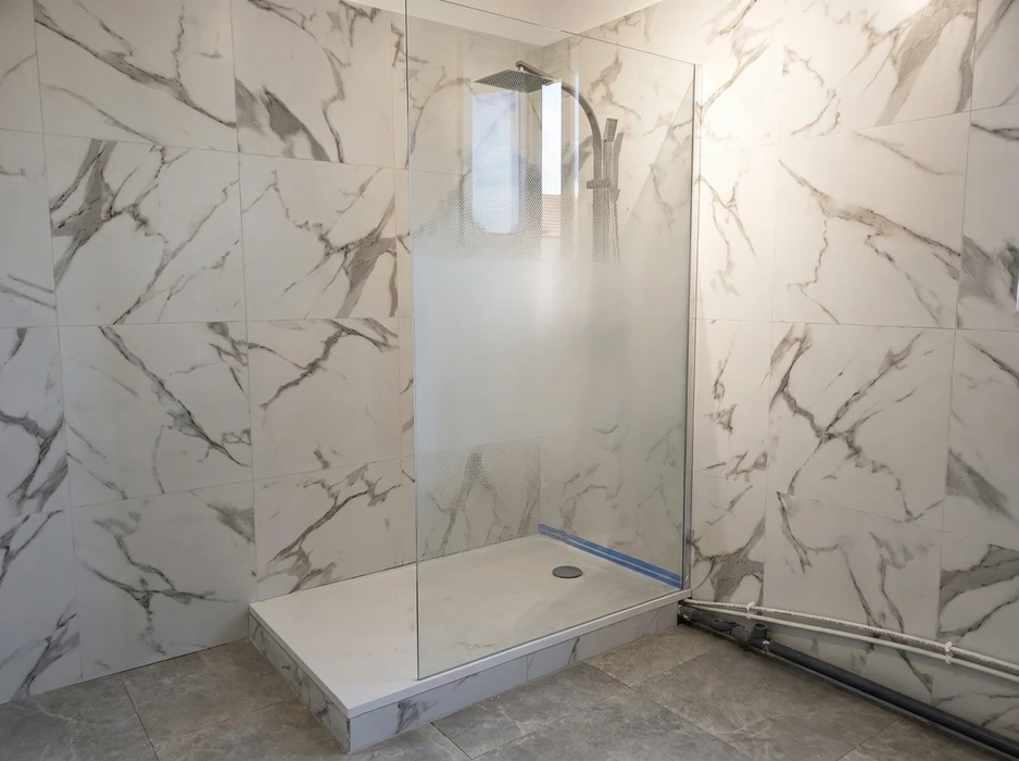 Salle de bain moderne avec douche à l'italienne, carrelage métro bleu-vert brillant sur mur accent, revêtement mural effet marbre blanc veiné gris