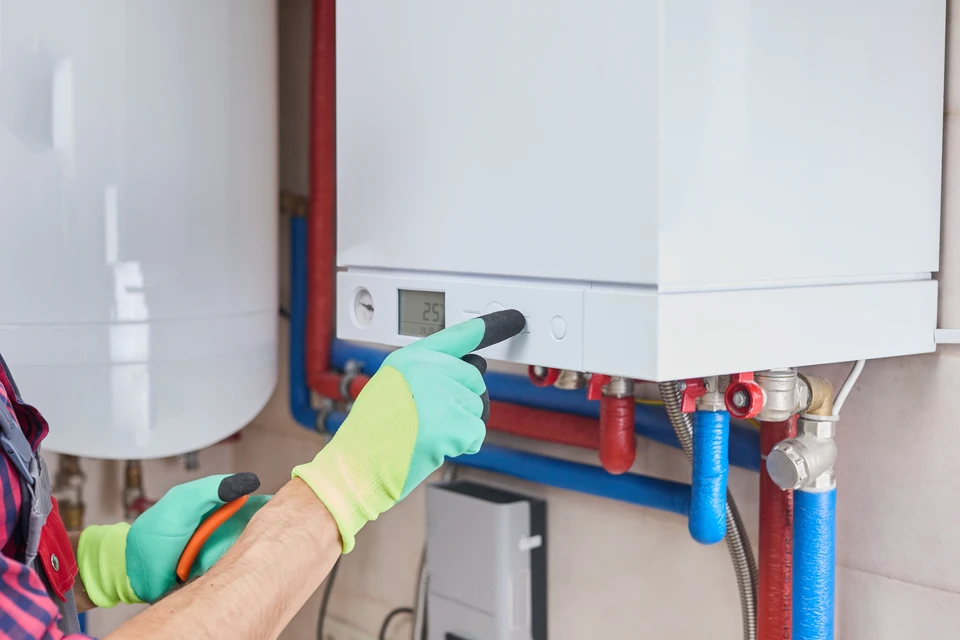 Plombier en salopette bleue travaillant à genoux dans salle de bain moderne, manipulant outils de plomberie